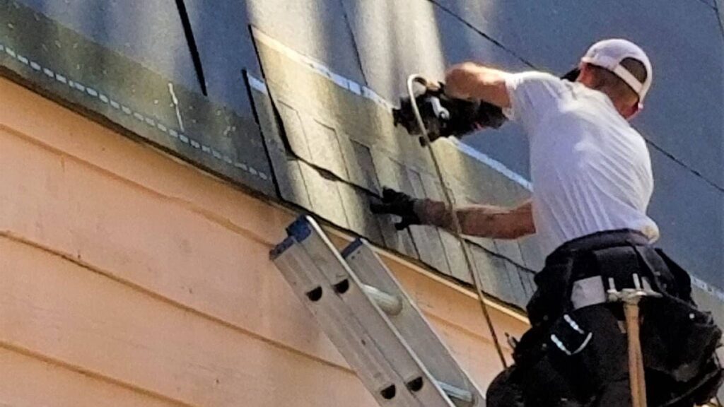 A crew member roofing an a frame home