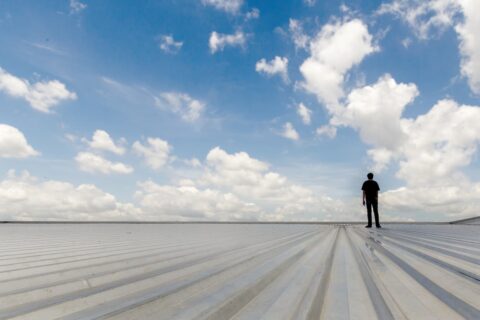 A person standing on the roof of a commercial building.