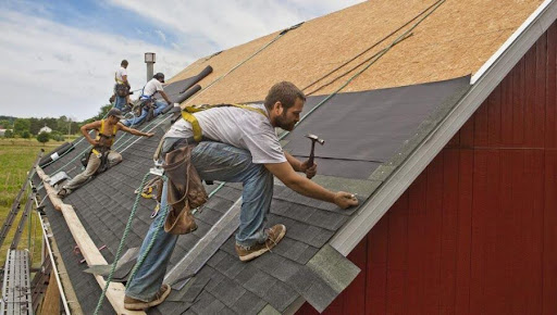 hand nailing asphalt shingles on a steep roof